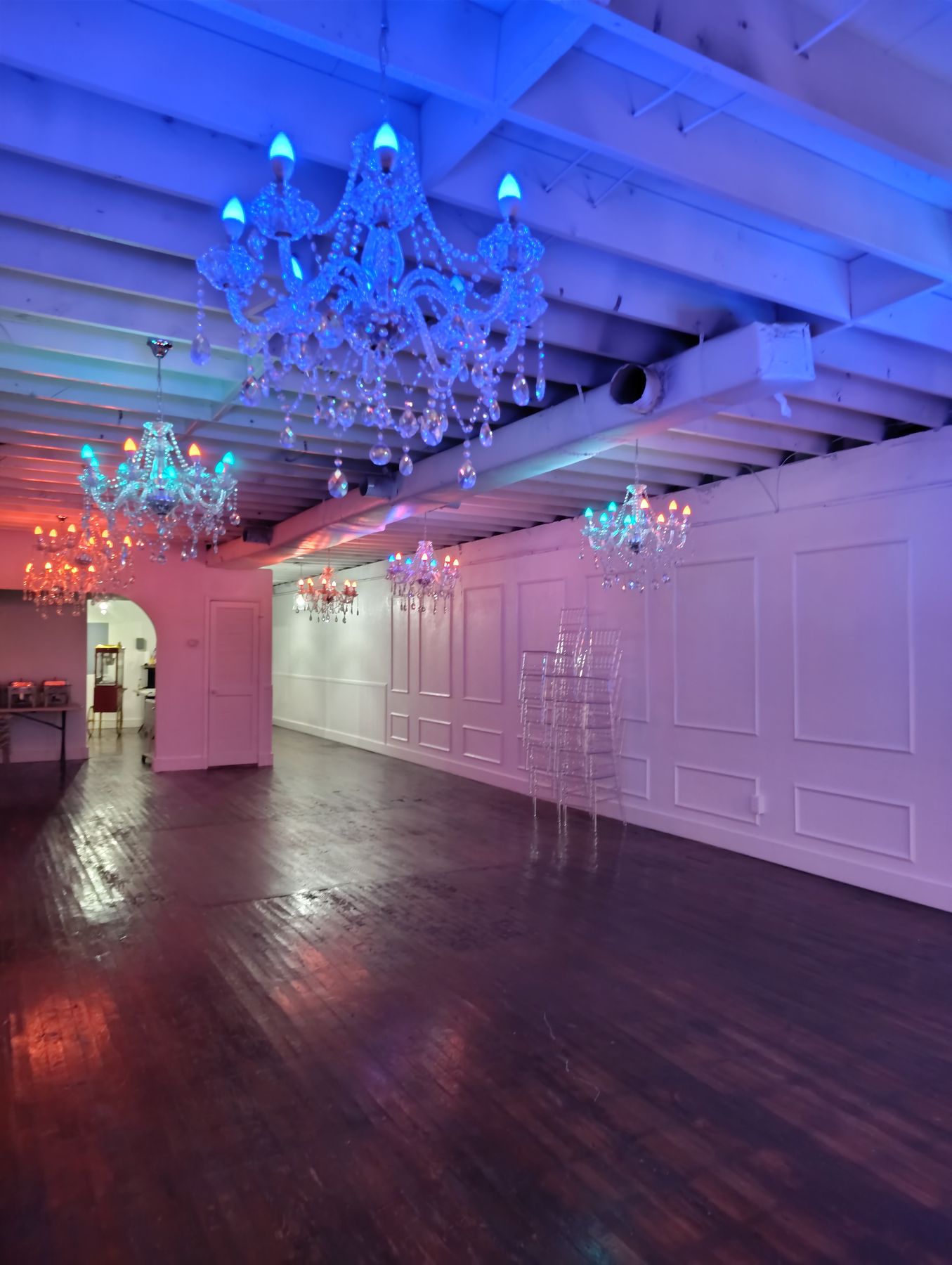 The Traditional Room washed in blue and pink uplighting, with chandeliers reflected in the polished dark hardwood floor